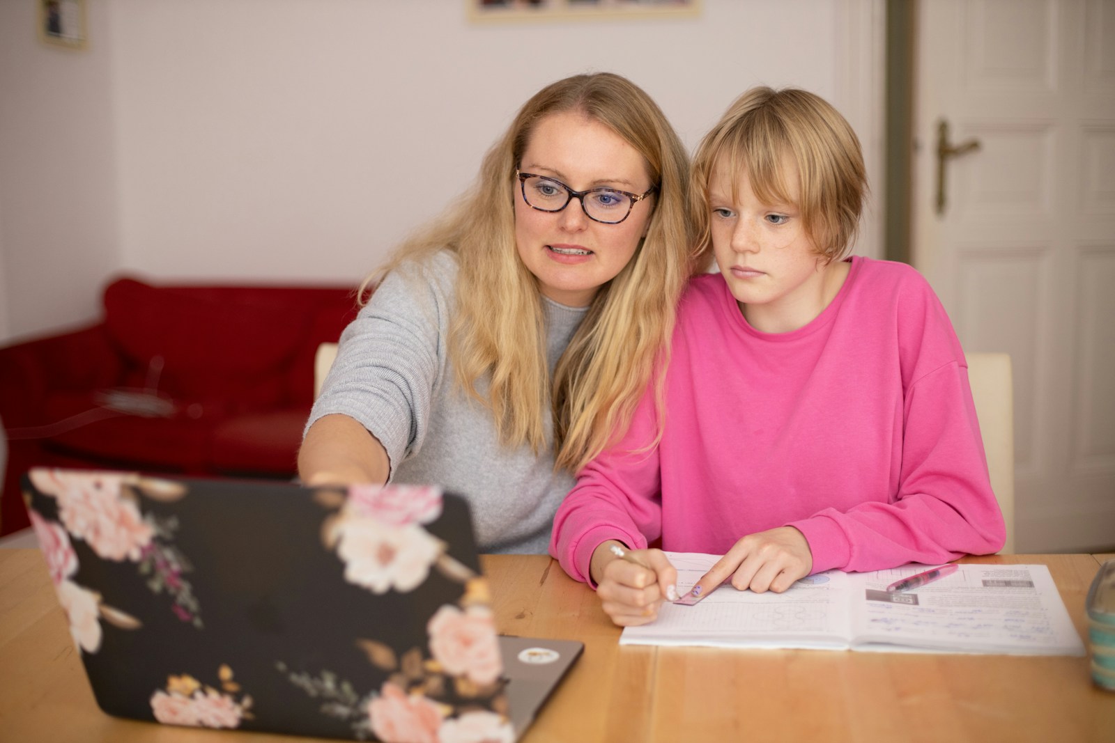 Mother and teenage student studying together at home with a laptop and notebook